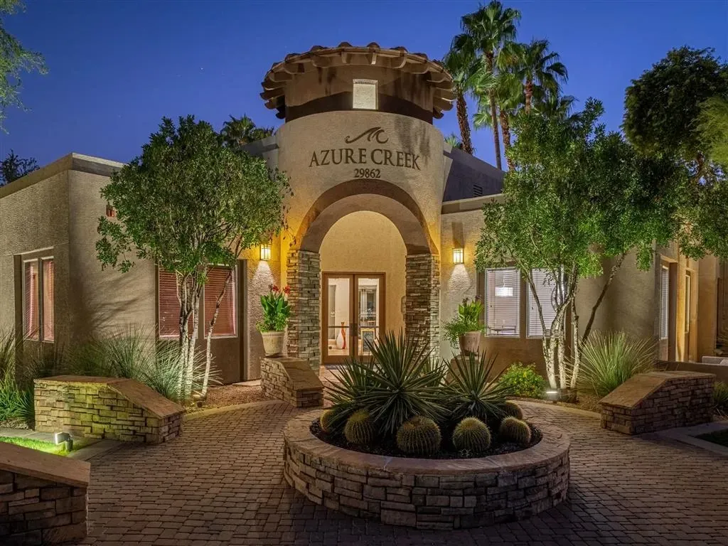 Azure Creek apartment building entrance with illuminated landscaping at dusk.