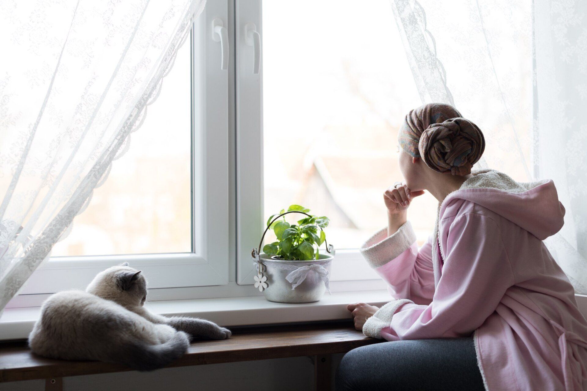Photo de femme en longue maladie devant une fenêtre