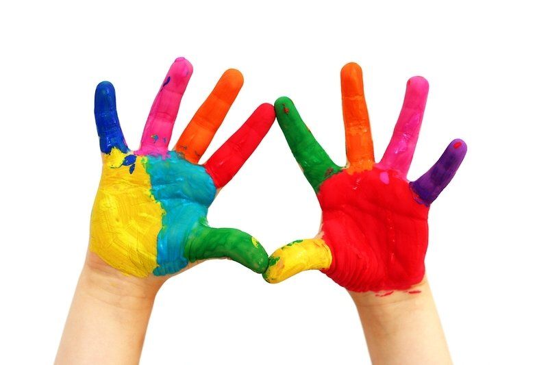 Les mains d'un enfant peintes de différentes couleurs forment une forme de cœur