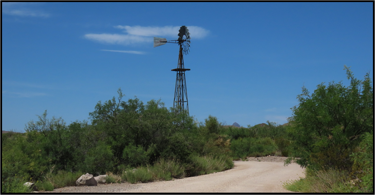 A windmill on the side of a dirt road