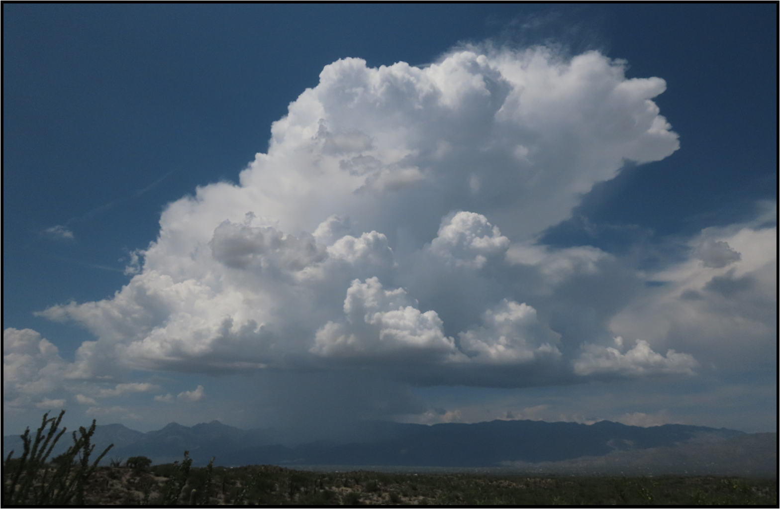 A large cloud in the sky with mountains in the background