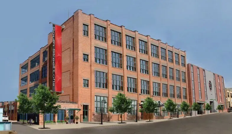 Brick mid-rise building with red vertical banner on a tree-lined city street
