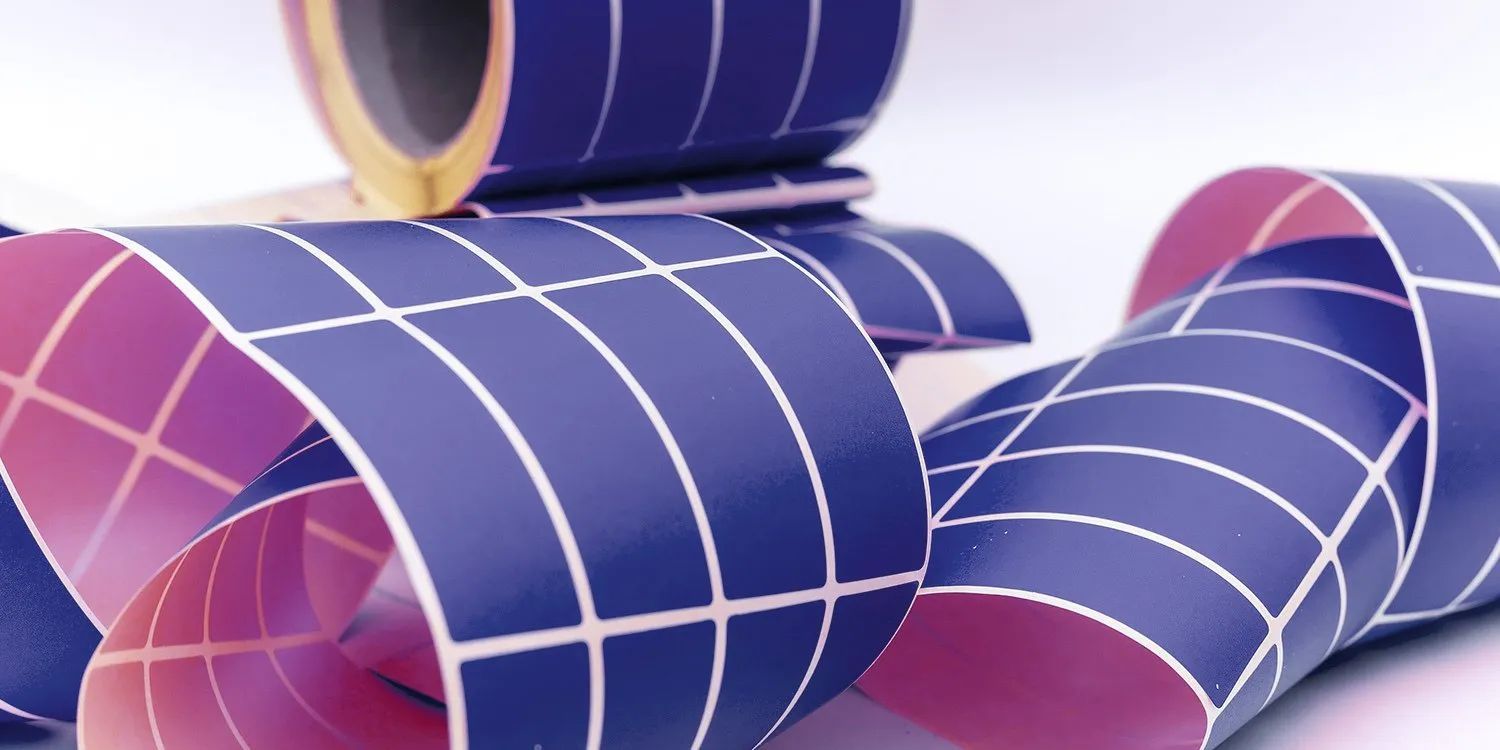 Rolled blue and purple grid-patterned sheets stacked and curling on a white surface