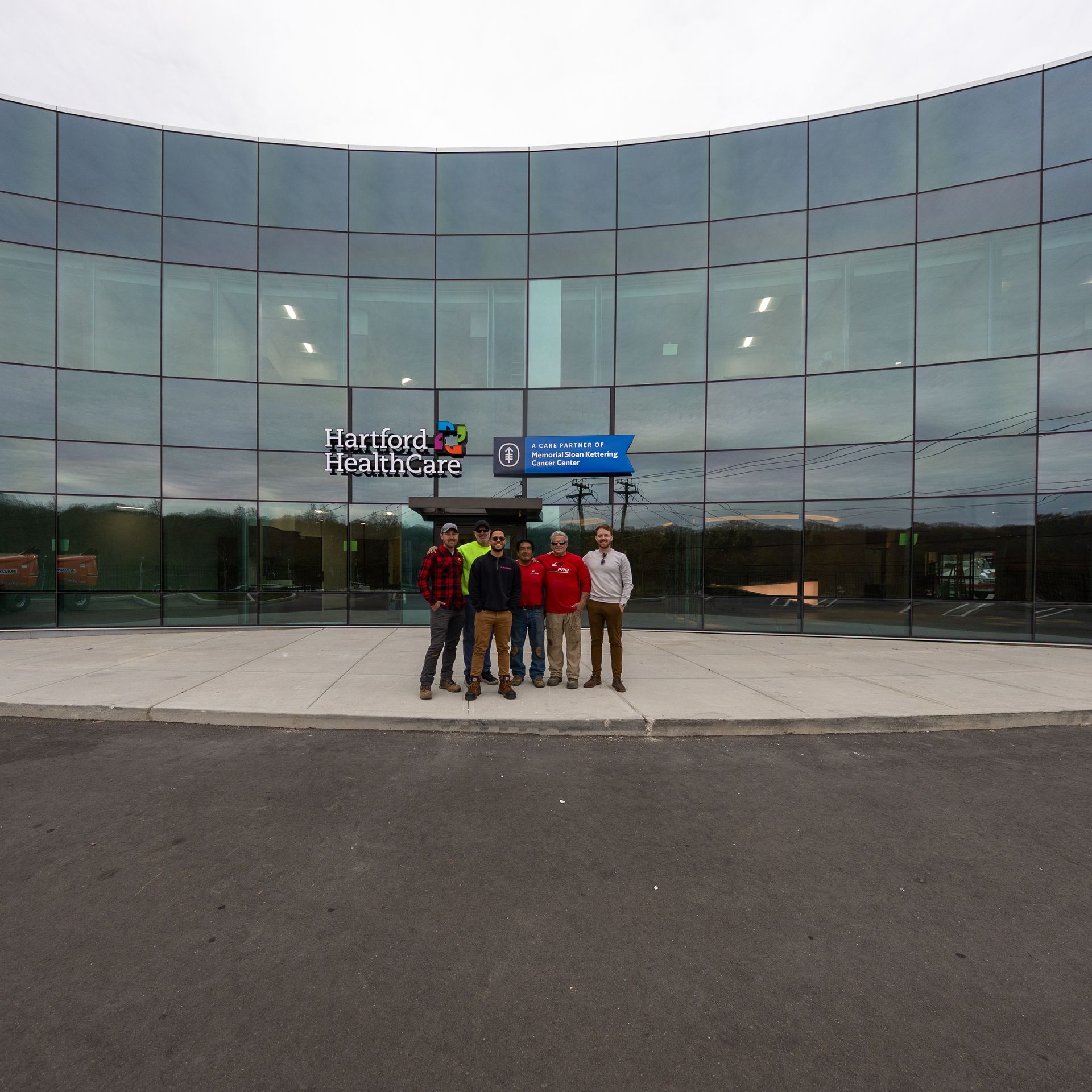 Five people standing in front of a curved glass building with the sign "Easton Area High School".