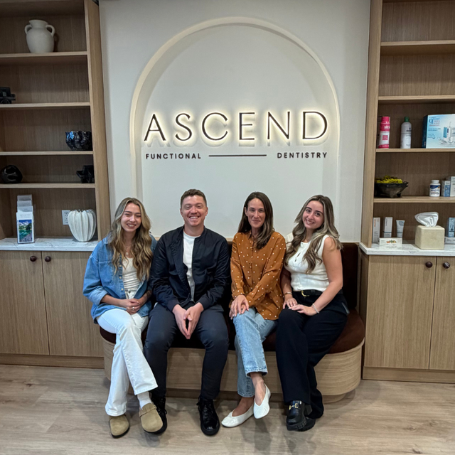 Four people seated in a dental office lobby under an ASCEND Functional + Cosmetic Dentistry sign.