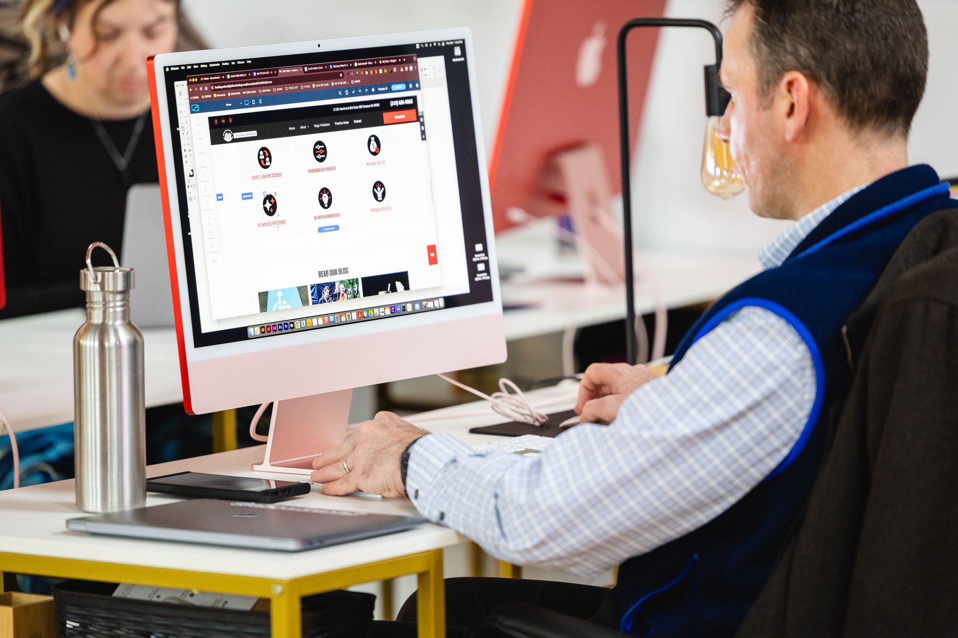 Person working at a desktop computer in an office, viewing a website on the monitor.