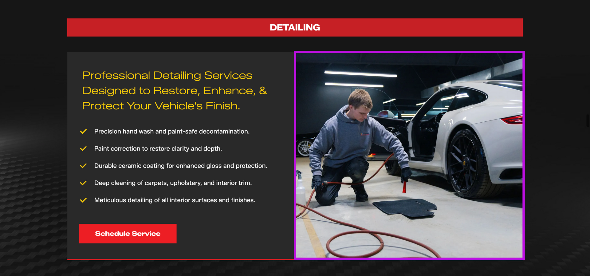 Mechanic kneeling beside a white car, inspecting the wheel with a hose in a garage.