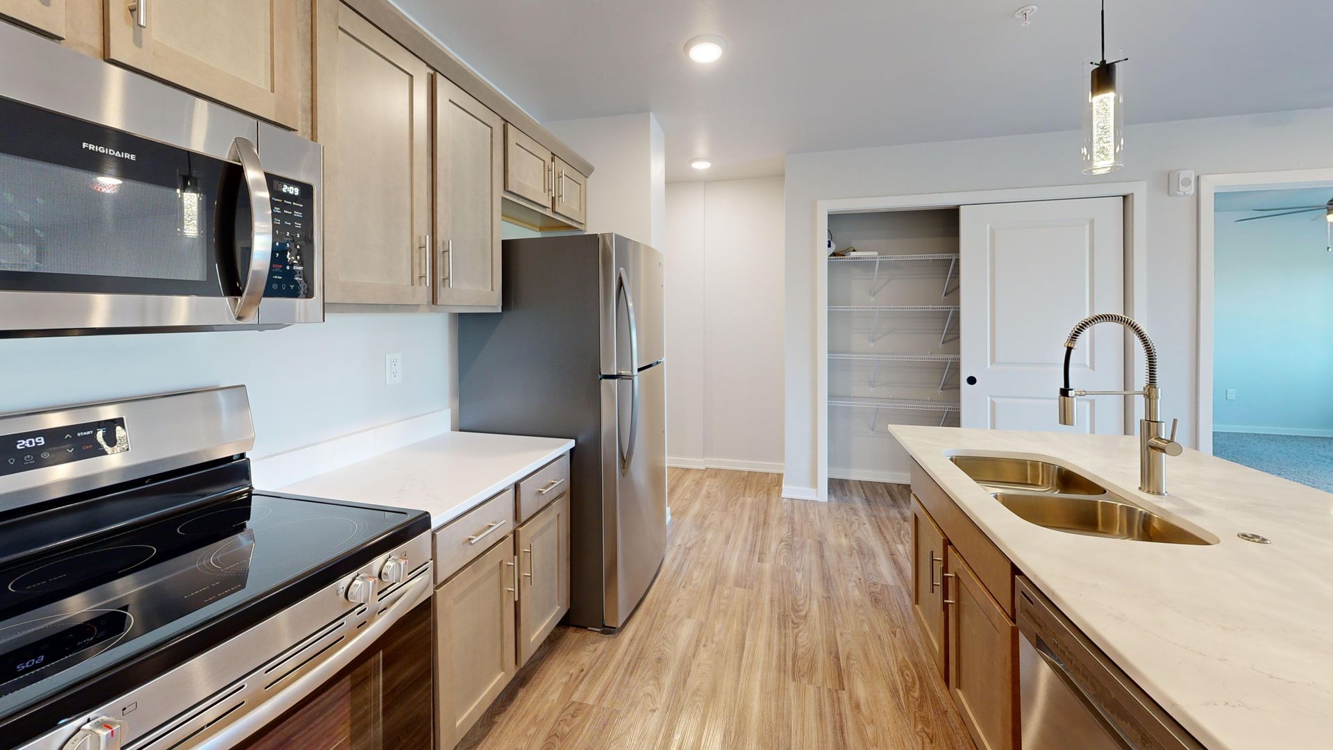 Modern kitchen with stainless steel appliances, white cabinets, island sink, and light wood floors