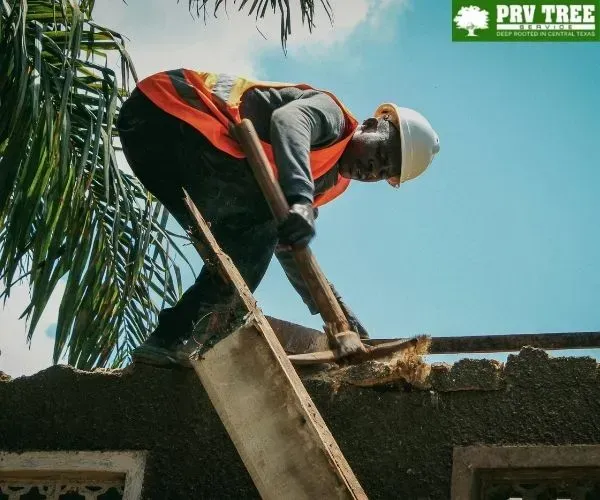 A construction worker in a hard hat and safety vest breaking down concrete using a tool.