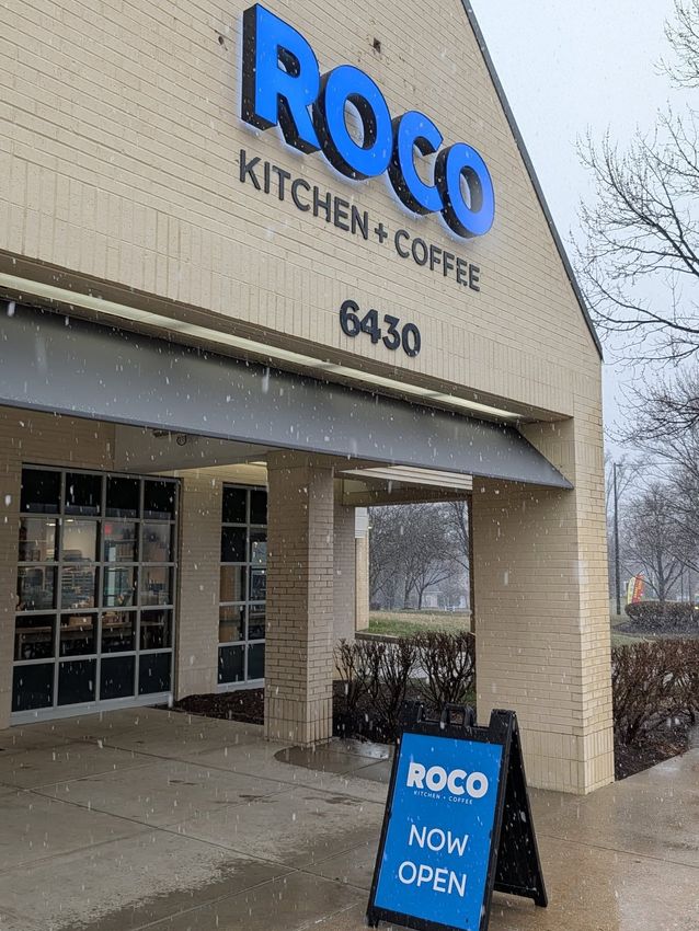 Roco Kitchen & Coffee storefront with blue sign and entrance awning on a snowy day