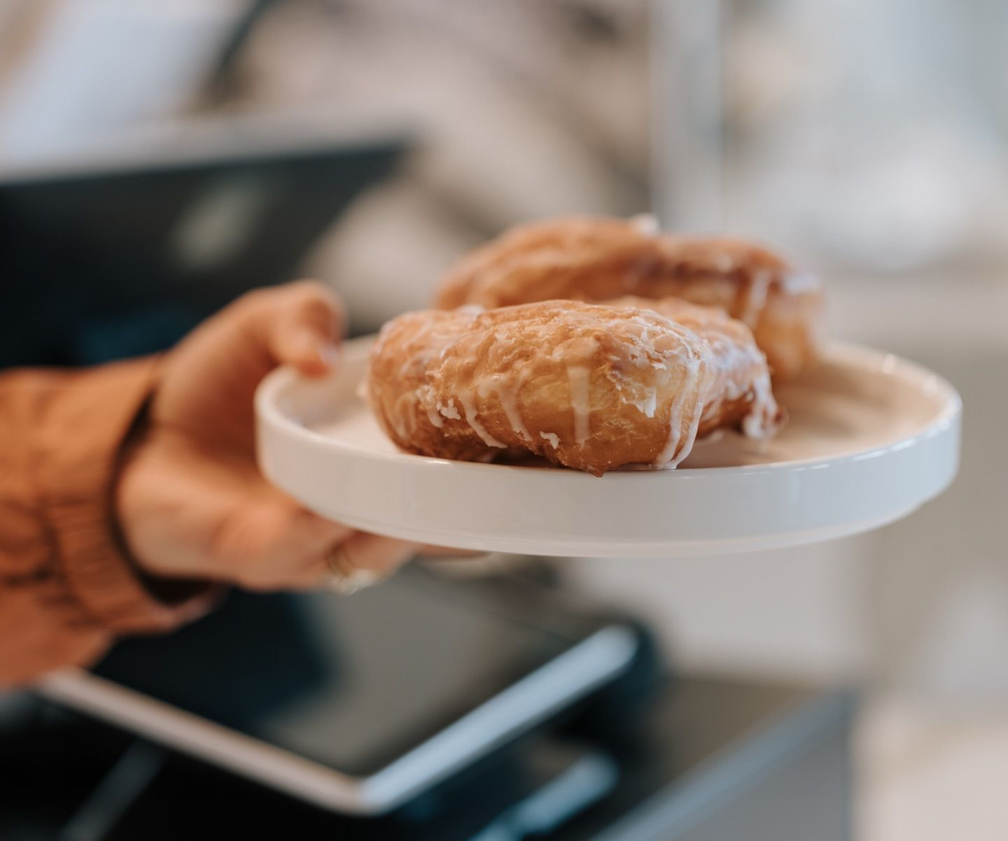 Handing a white plate with two glazed pastries in a bakery