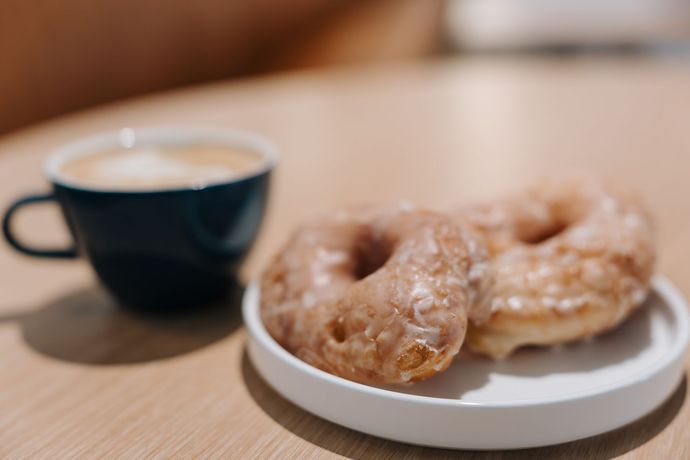 Black coffee and glazed donuts on a wooden table