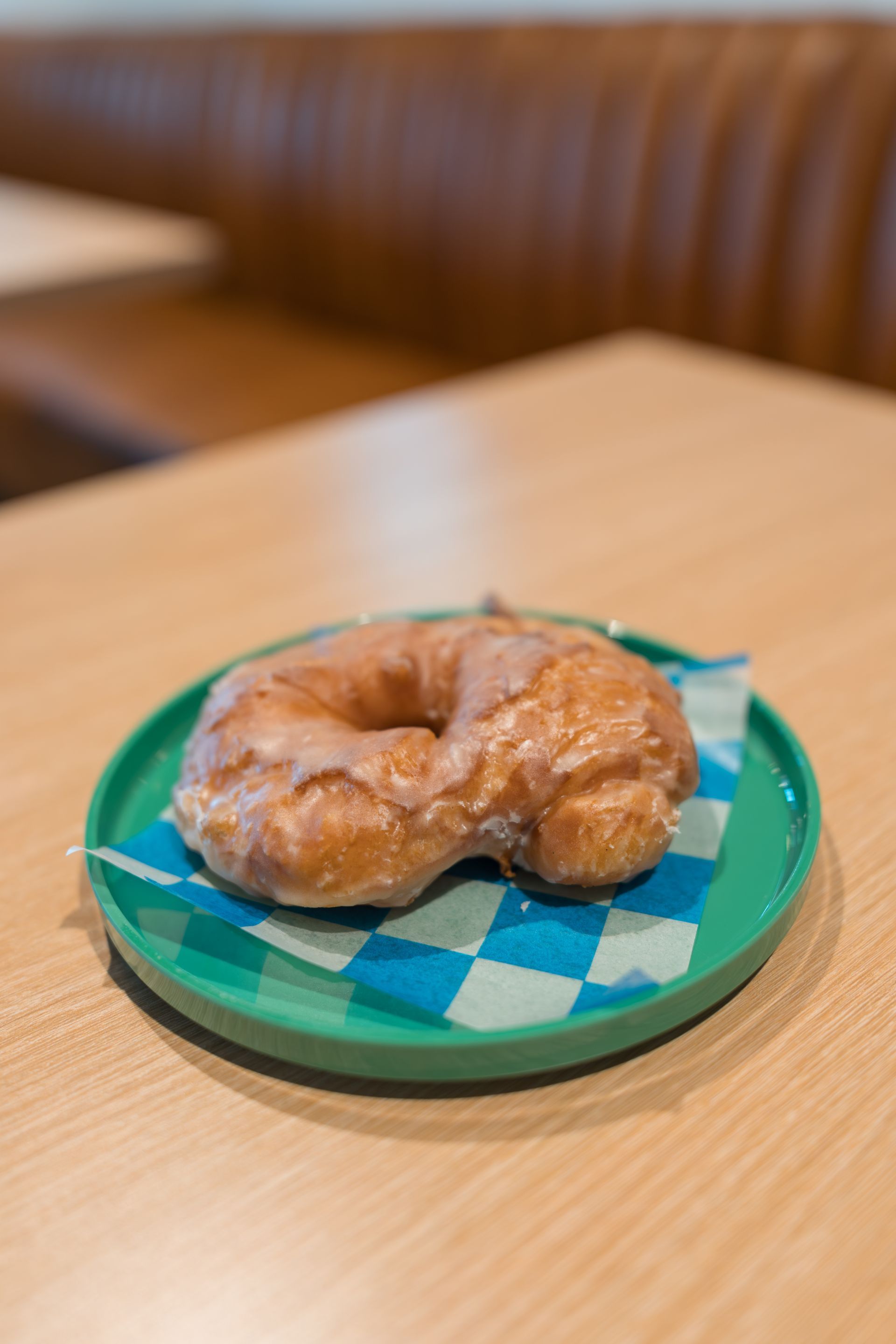 Croissant on a teal checkered plate on a wooden table in a café