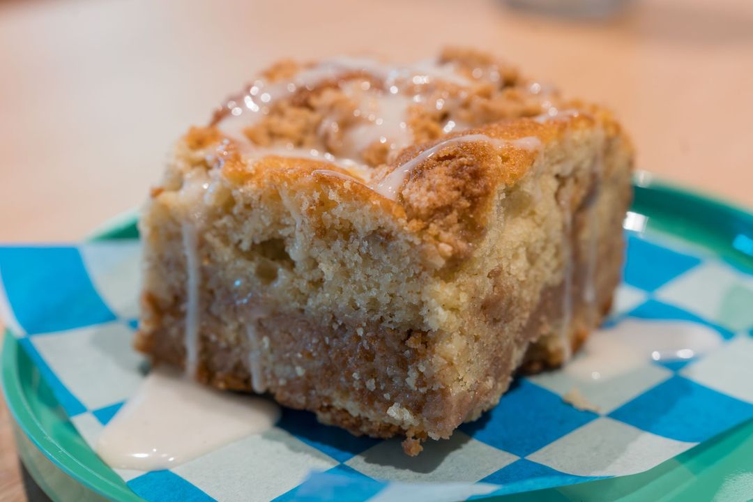 Cinnamon coffee cake square on a blue checkered plate with icing drizzle
