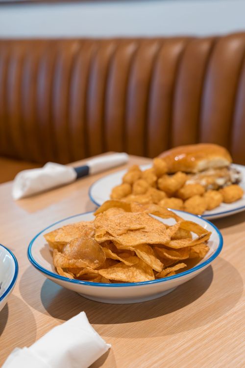 Bowls of chips and fried snacks on a restaurant table with a brown leather booth in the background