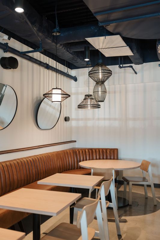 Modern café interior with wooden tables, benches, round mirrors, and hanging pendant lights