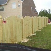 A wooden fence is sitting in the grass in front of a house.
