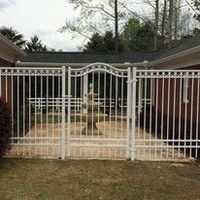 A white wrought iron gate is in front of a brick house.