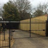 A wrought iron gate is surrounding a parking lot.
