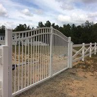 A white aluminum gate is sitting next to a white fence.
