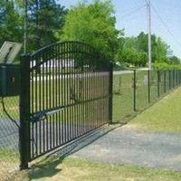 A black wrought iron gate is surrounded by a chain link fence.
