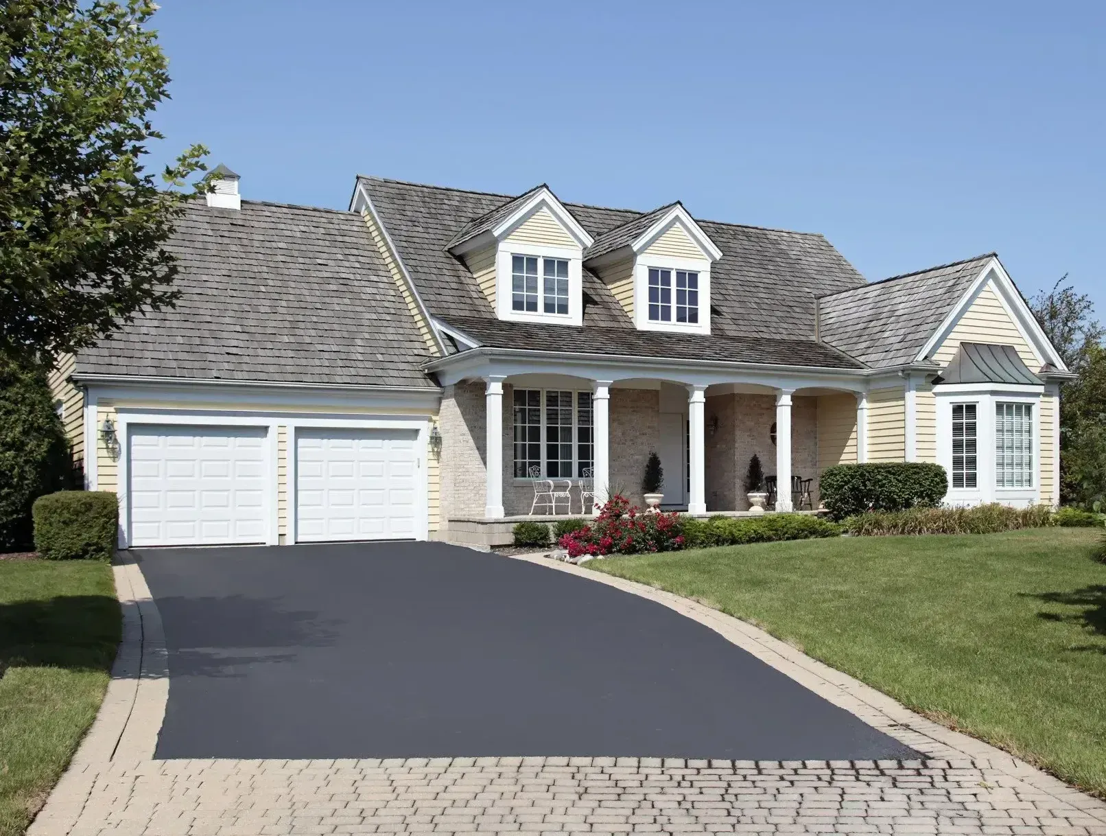 A large house with two garage doors and a driveway leading to it.