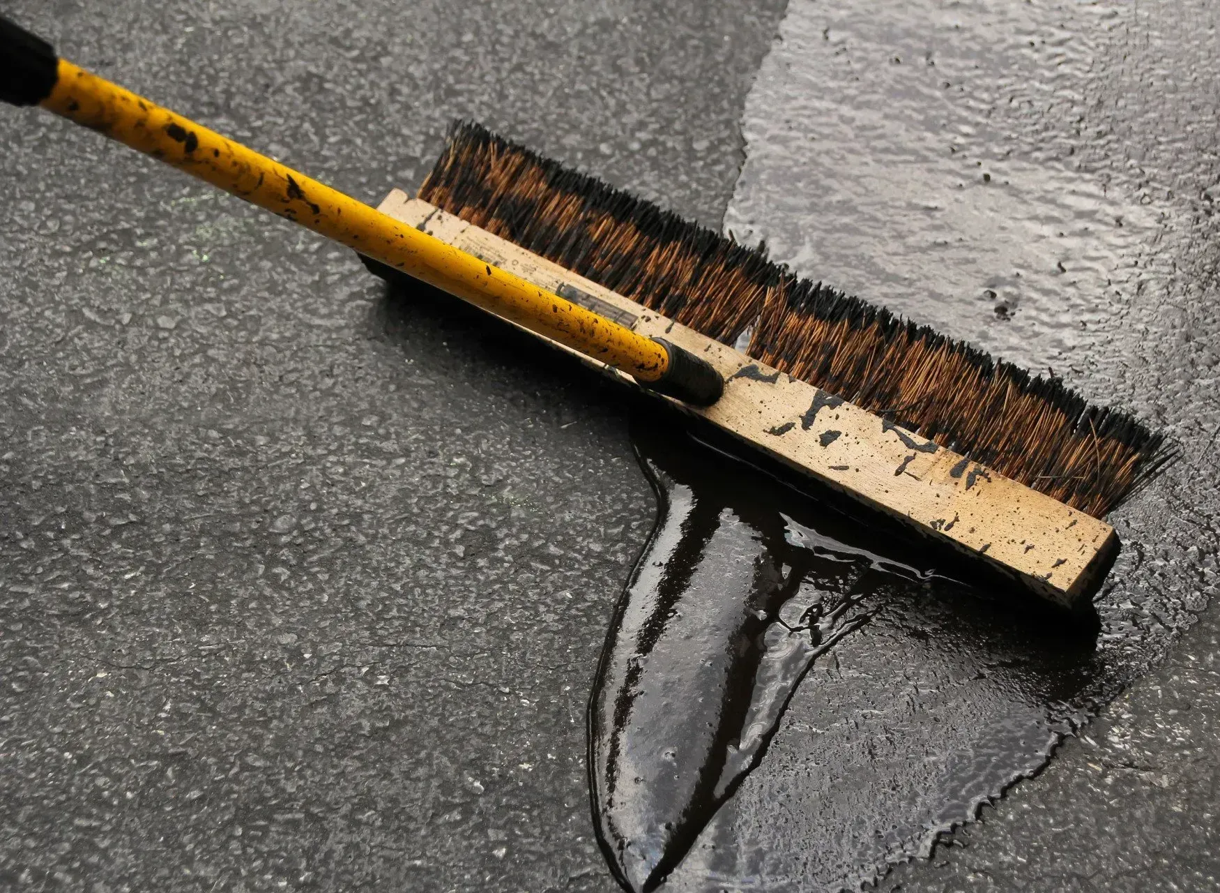 A broom is being used to clean a puddle of water on the ground