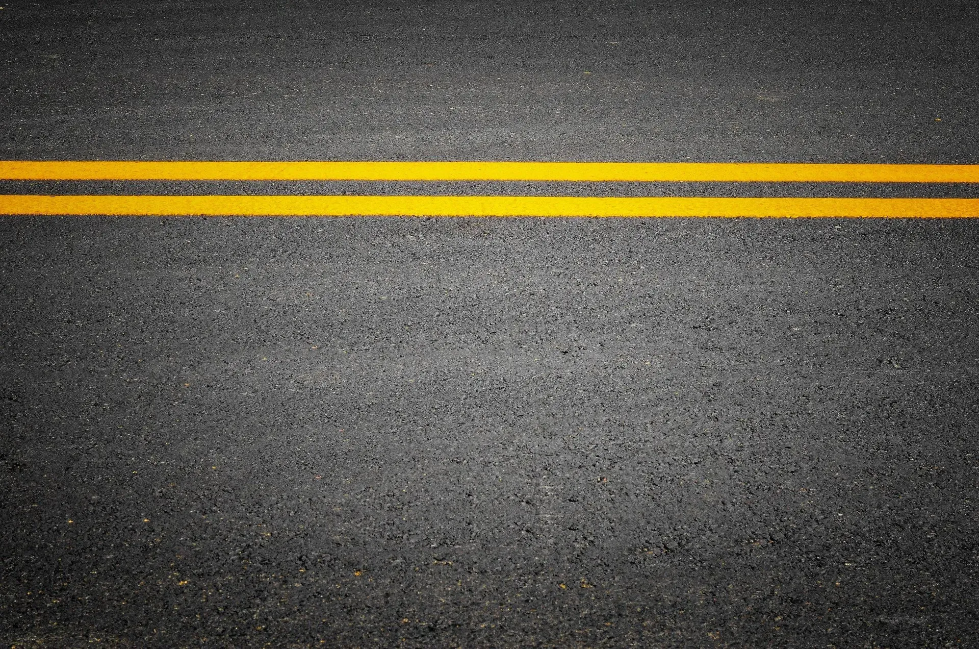 A close up of a road with two yellow lines on it.