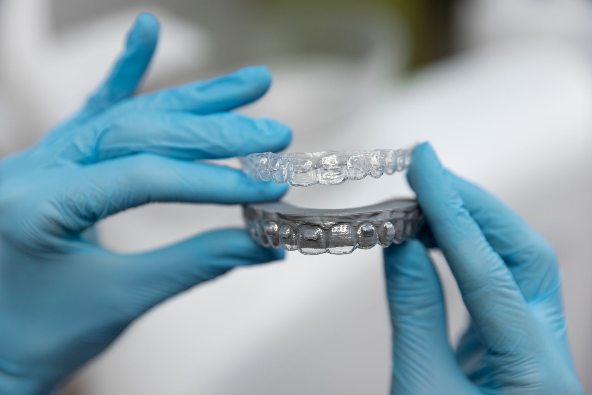 Dentist examining a patient's teeth with tools, the patient wearing protective glasses, indoor setting.