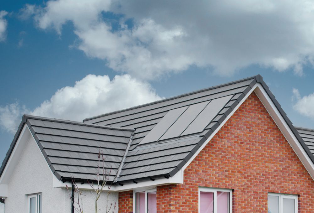 Red brick house with gray roof and solar panels under a blue sky