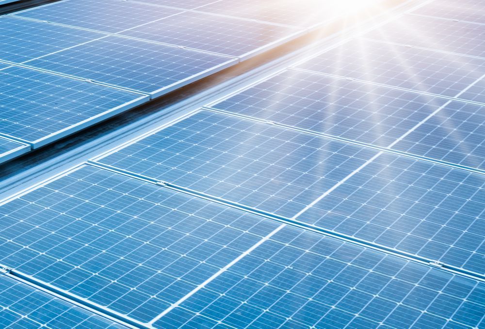 Rows of blue solar panels reflecting sunlight under a bright sky