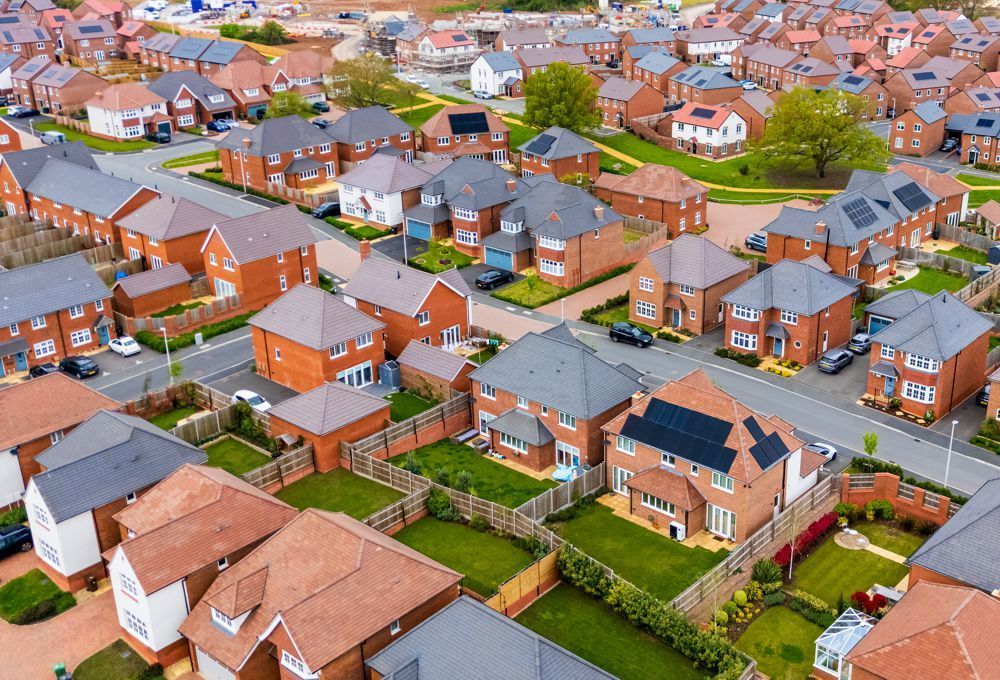 Aerial view of a suburban neighborhood with brick houses, green lawns, and curving streets