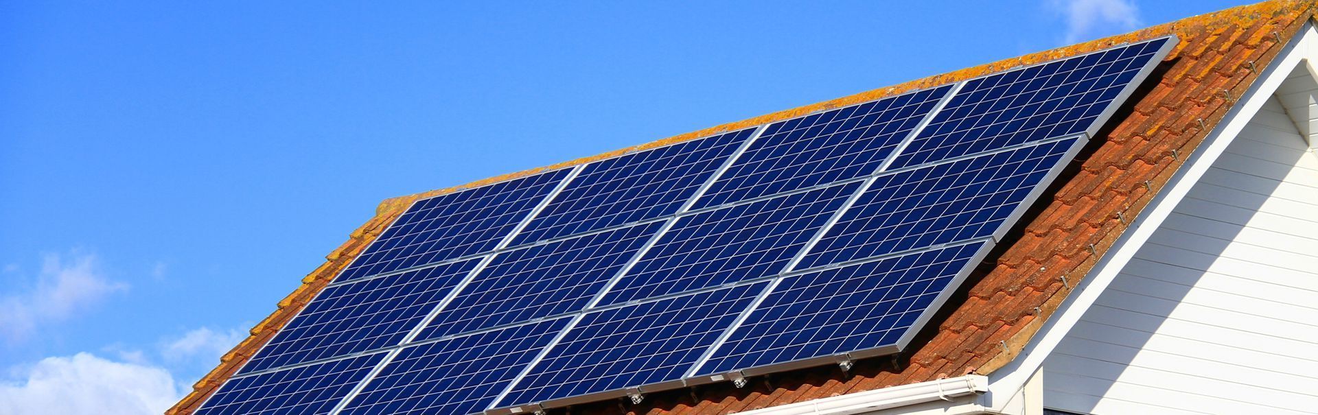 Solar panels mounted on a sloped rooftop under a blue sky
