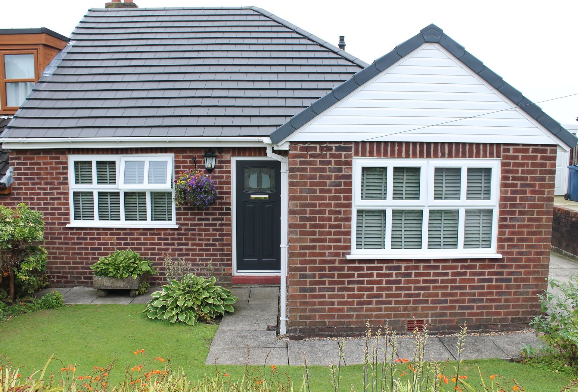 Small brick house with white trim, dark door, and front garden.