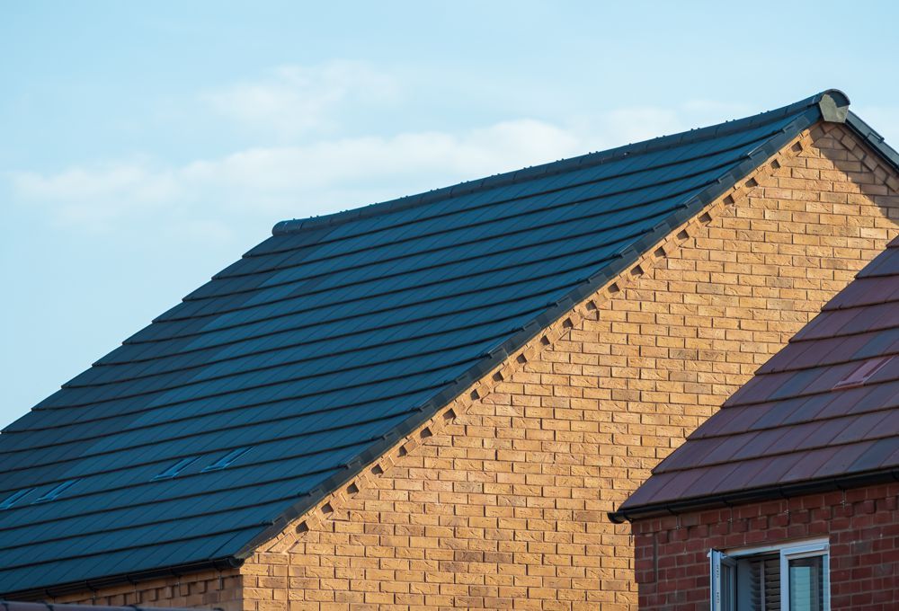 Two rooftops with dark blue and brown shingles against a blue sky