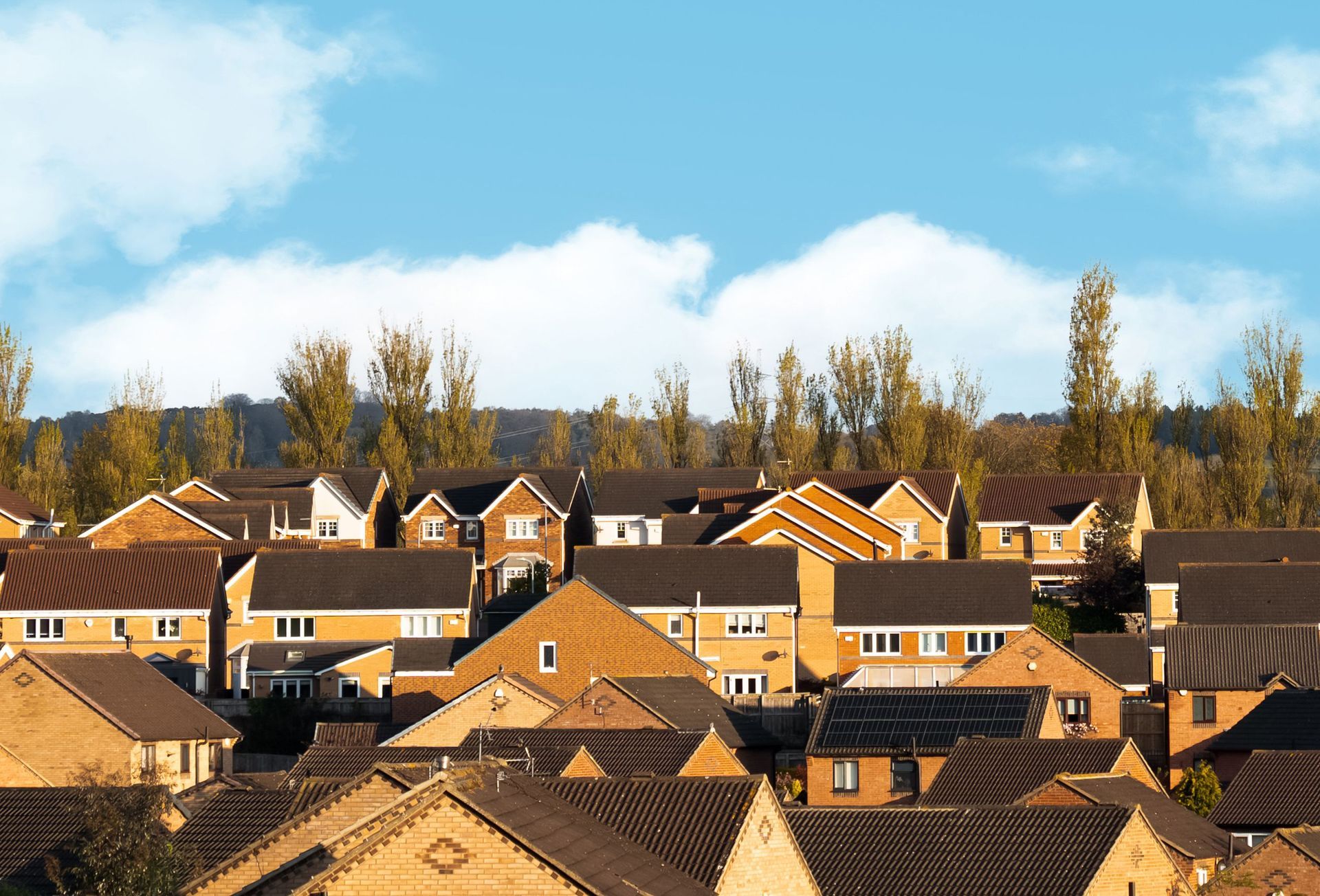 Suburban neighborhood with terracotta rooftops under a blue sky and autumn trees