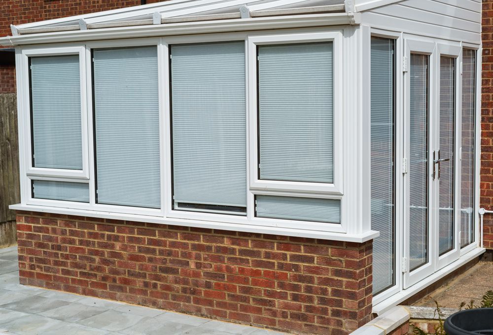 Brick-and-white sunroom with frosted windows and glass doors on a patio