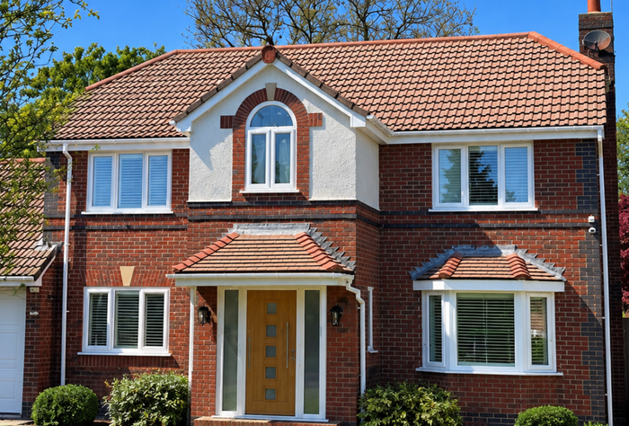 Two-story red-brick house with white trim, tiled roof, and central front door
