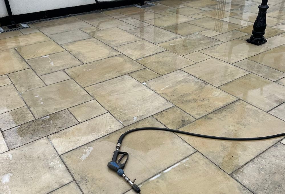 Tiled pavement with a black cable and plug lying across the ground near a lamppost base