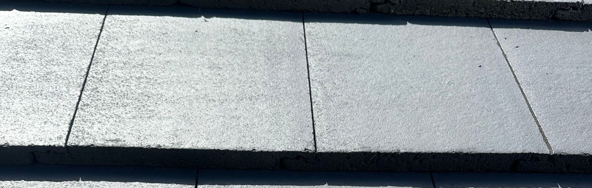 Gray concrete sidewalk slabs with dark seams and a curb edge