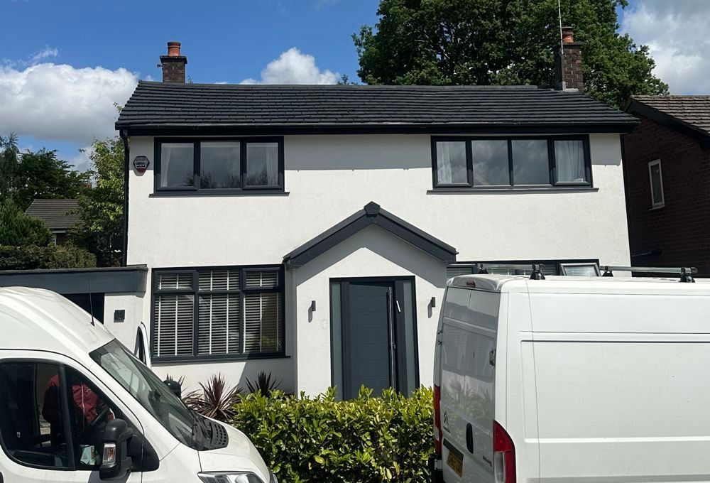 White two-story house with dark trim and parked vans in front
