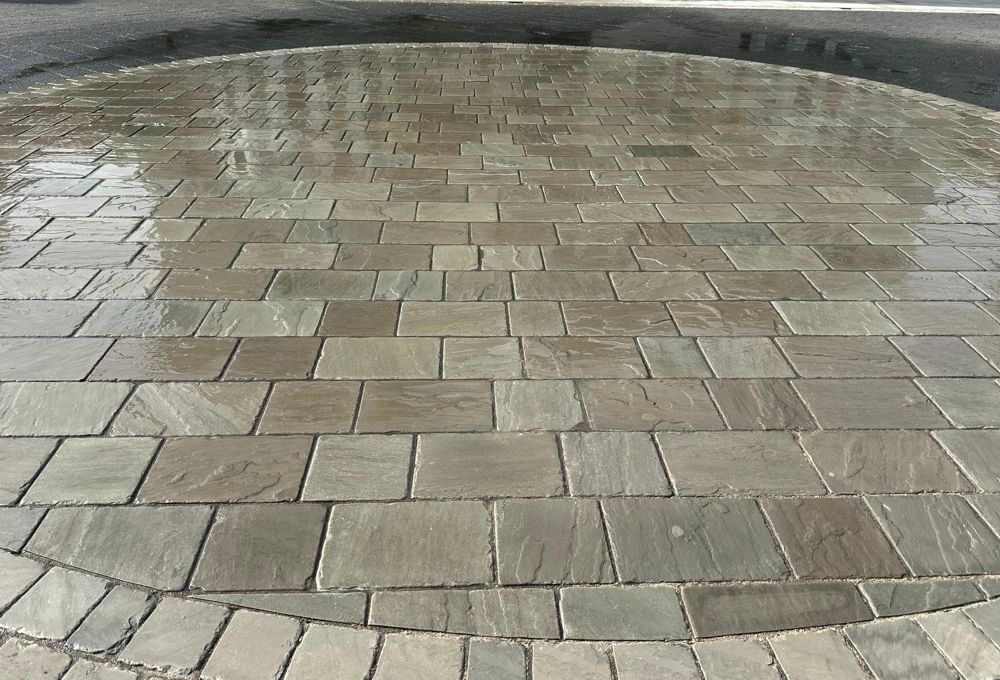 Curved stone-paved walkway with wet, gray rectangular tiles outdoors
