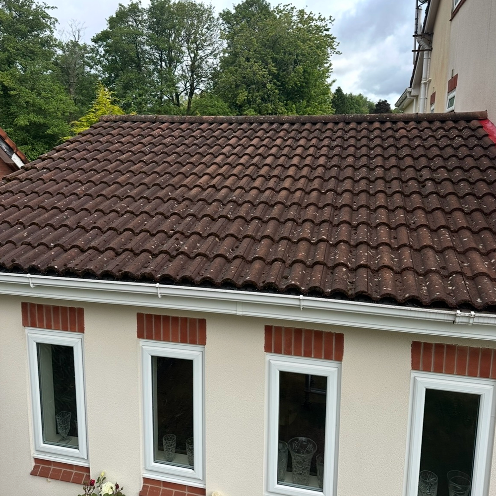 Small cream house with a brown tiled roof and four windows, viewed from above.
