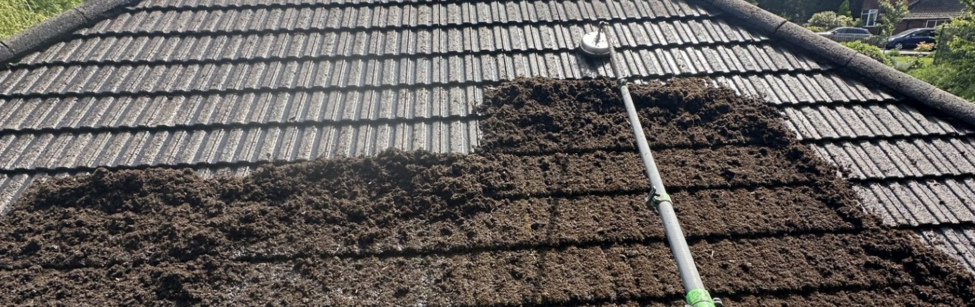 Roof covered with debris and a pressure-washing hose cleaning the surface