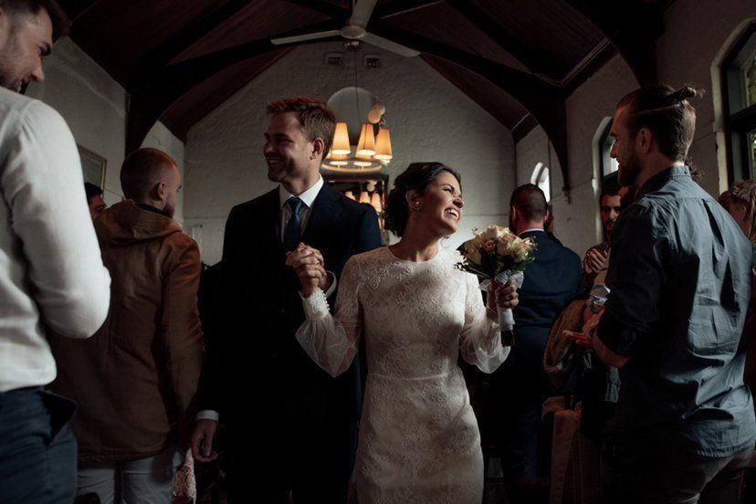 A bride and groom are walking through a crowd of people at their wedding reception.