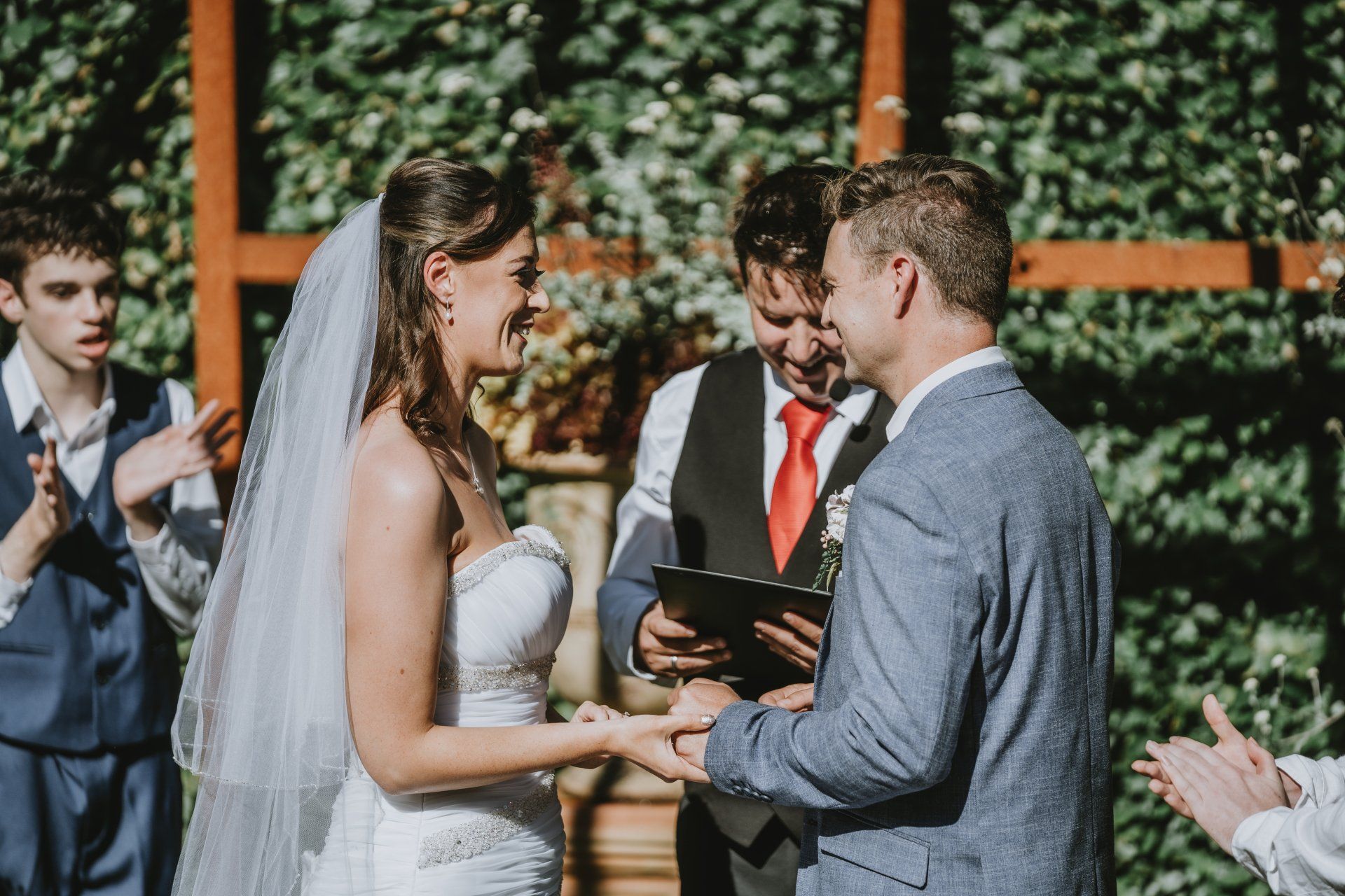 A bride and groom are holding hands during their wedding ceremony.