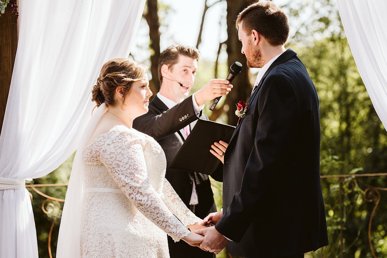 A bride and groom are holding hands during their wedding ceremony.