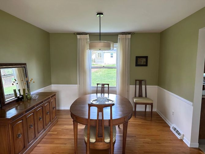A dining room with a table and chairs and green walls