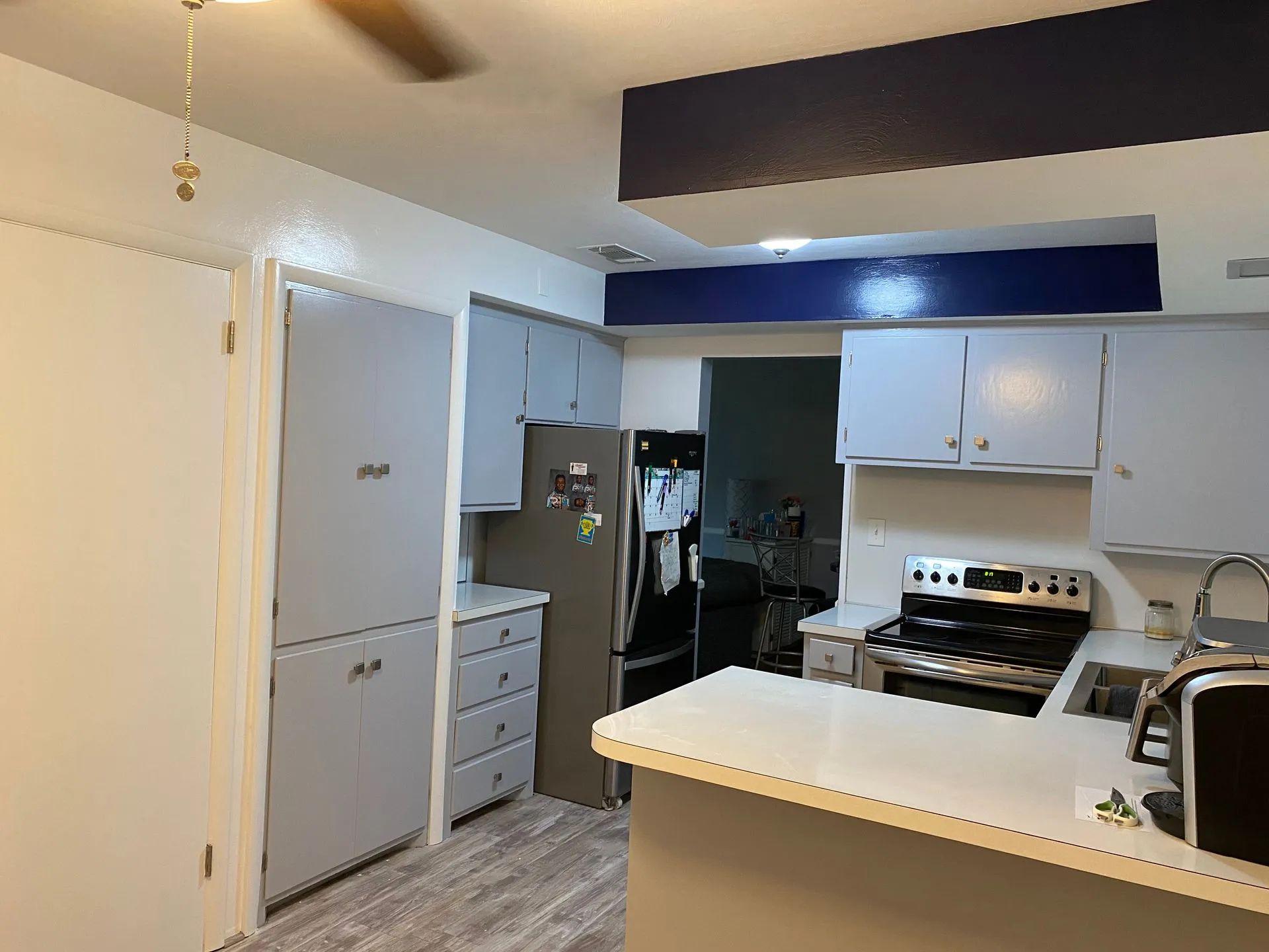 A kitchen with a stove , refrigerator , sink and a ceiling fan.