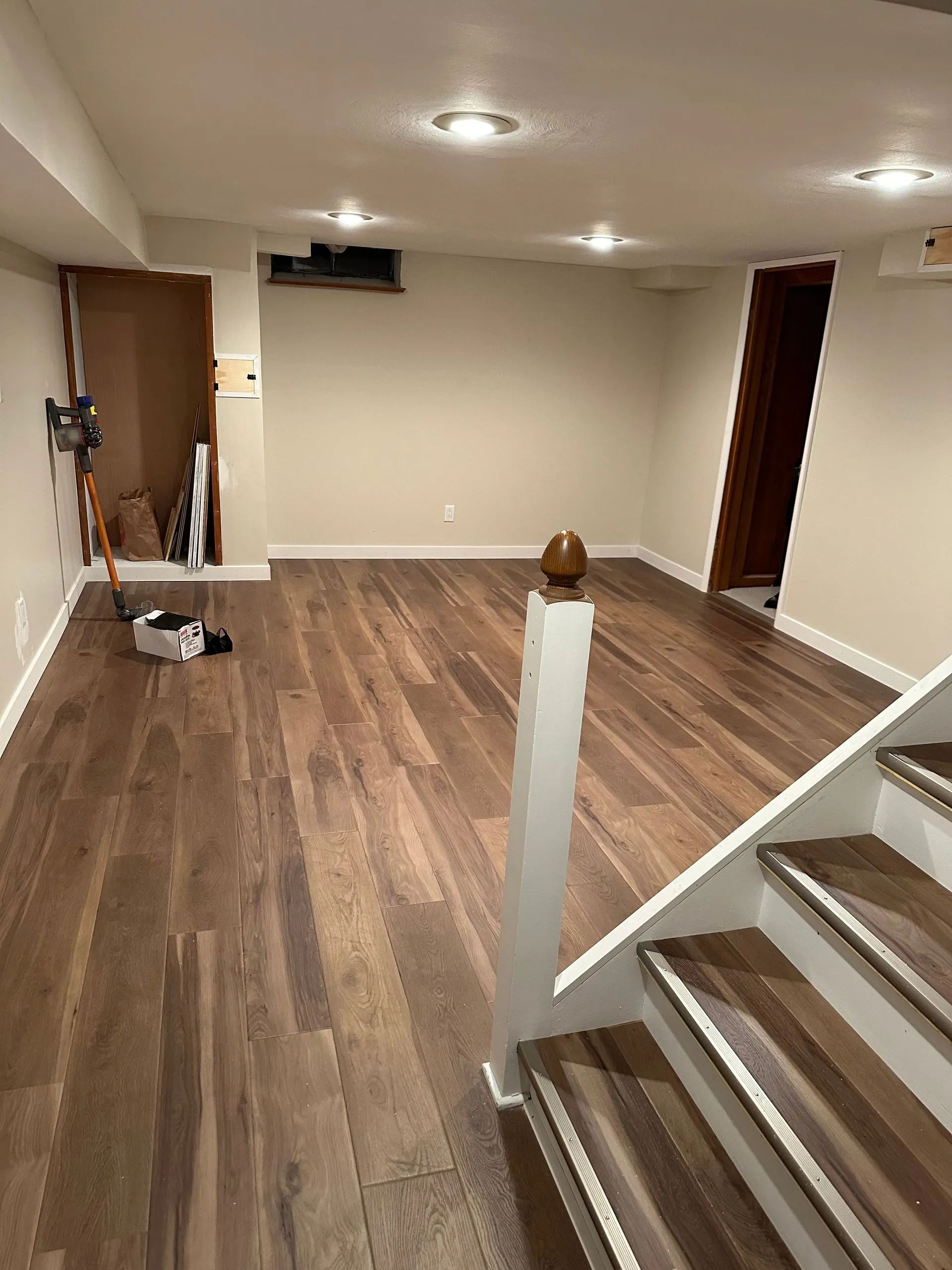 A basement with hardwood floors and stairs.